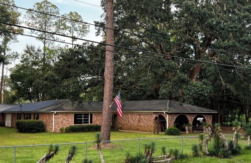 Moss Point House | Large fenced in home under a giant, moss covered, southern oak tree.