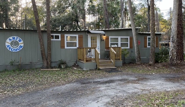 Step into this cozy 2-bedroom cabin nestled in the tranquil woods. The main living area offers comfy seating, including a pull-out futon for additional sleeping space. An efficiency kitchen awaits your culinary adventures, equipped with essentials fo in Inglis